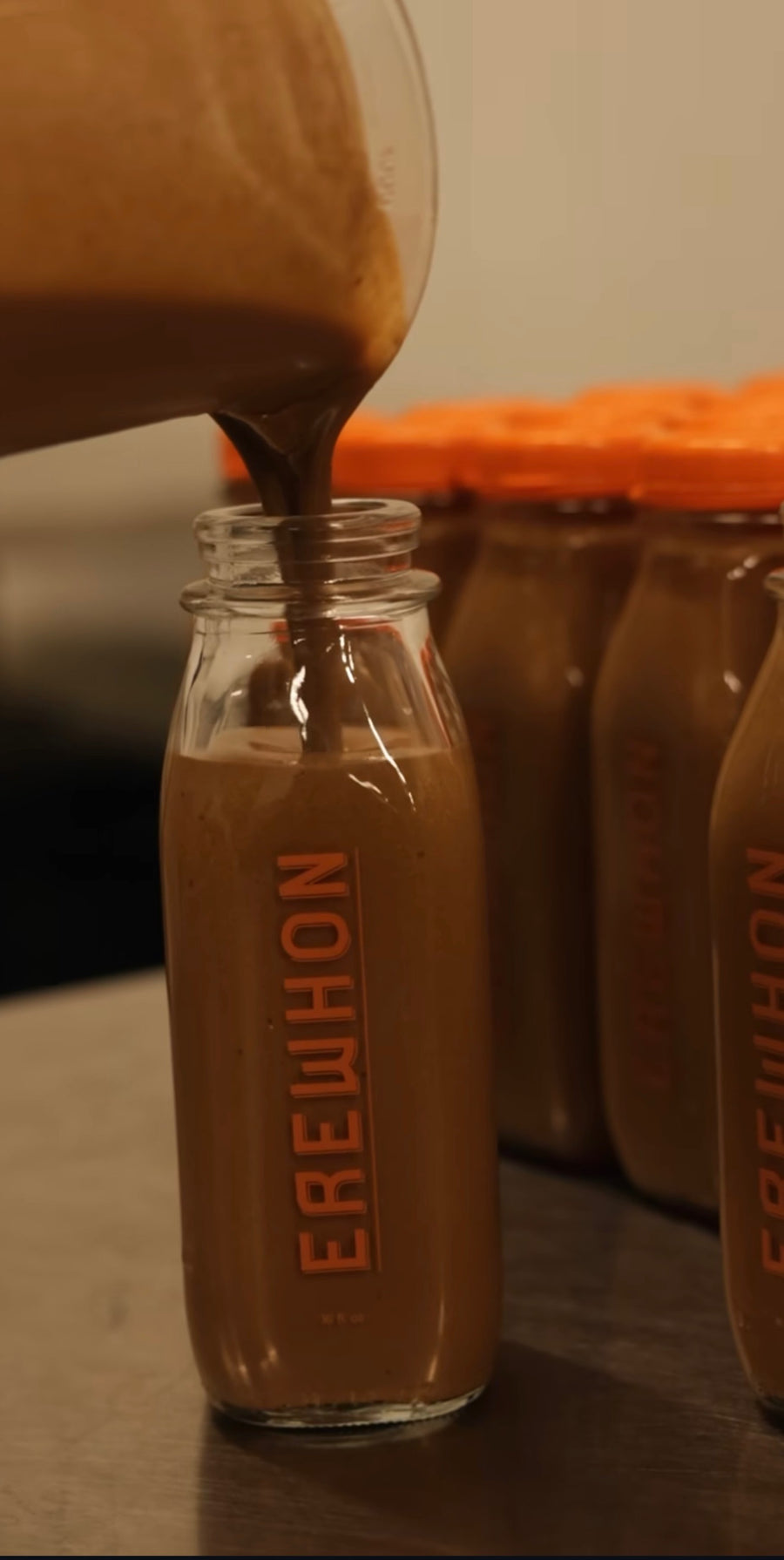 A blended drink being poured into a glass Erewhon bottle