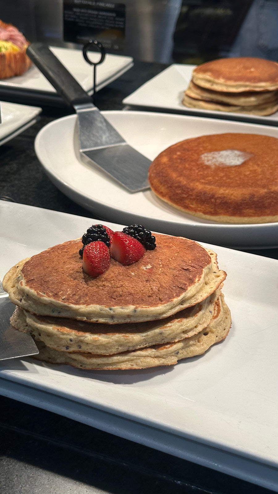 A stack of Erewhon chocho protein pancakes with berries and maple syrup