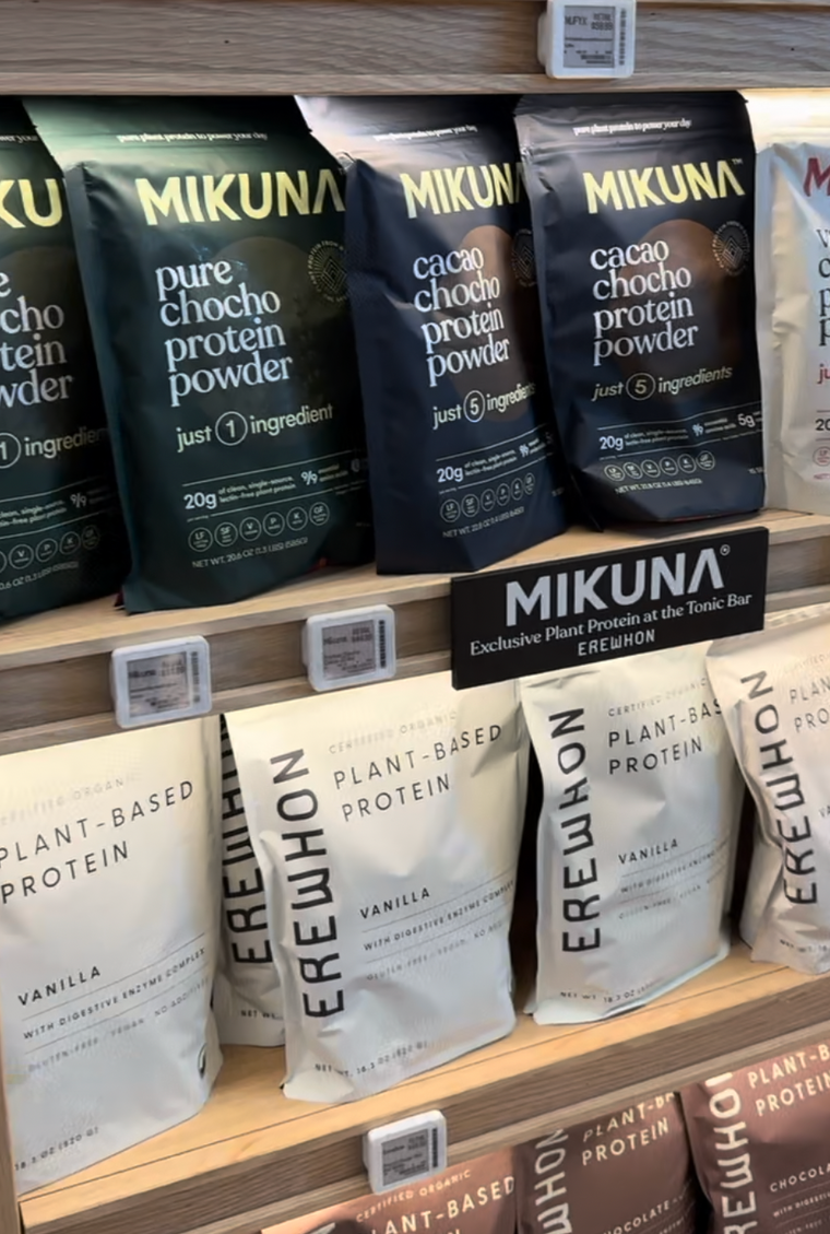 A MIKUNA Chocho Plant Protein bag held up in an Erewhon aisle